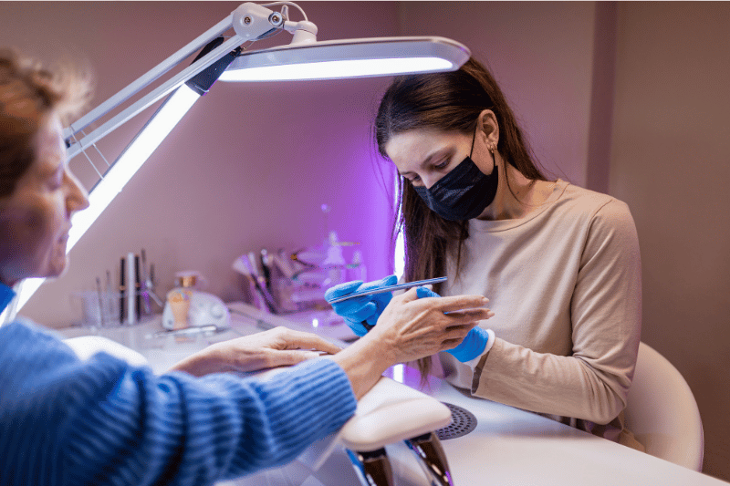 Manicure realizando atendimento em cliente, mostrando cuidado e processo de um serviço prestado