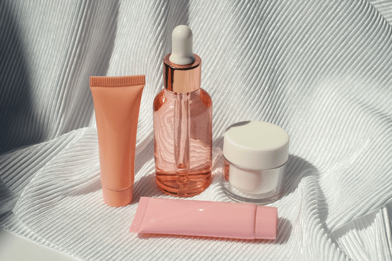 Produtos de skincare organizados sobre tecido claro, incluindo sérum, creme e hidratante